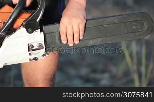 Close up view of man holding chainsaw and removing the protective housing