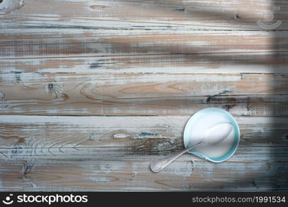 Close-up view of milk and spoon in small bowl over wooden table.