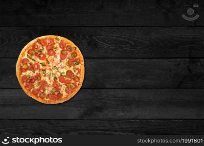 Close up view of rounded pizza isolated on black wooden table.