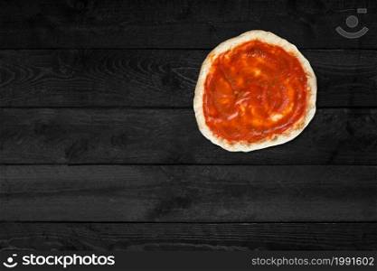 Close up view of rounded pizza isolated on black wooden table.