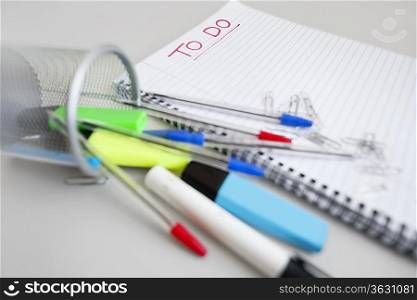 Close-up view of spiral notebook with to-do list and office supplies