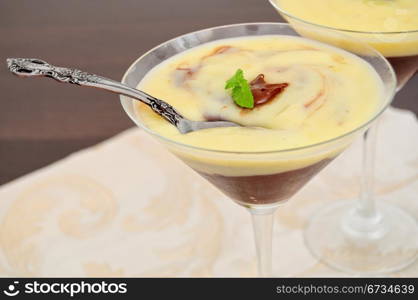 Close up view of spoon in chocolate and vanilla cream, served in glass