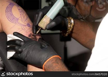 Close up view of tattooing process. Master makes contouring lines with his professional tattoo machine. High quality photography. Close up view of tattooing process. Master makes contouring lines with his professional tattoo machine.