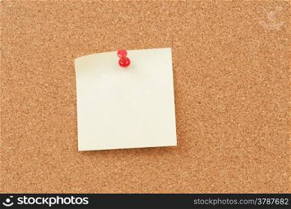close up view of thumbtack and note on corkboard