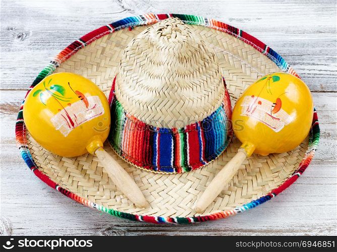 Close up view of traditional maracas and a large sombrero for Cinco de Mayo holiday celebration on weathered white wooden boards