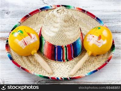 Close up view of traditional maracas and a large sombrero for Cinco de Mayo holiday celebration on weathered white wooden boards