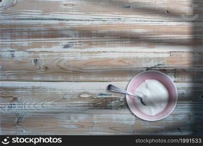 Close up view of white butter cream on small bowl over wooden table.