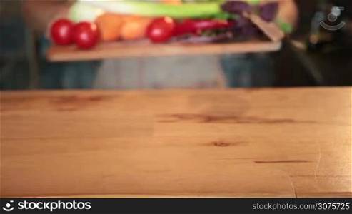Close up view of woman&acute;s hands putting on the wooden table fresh vegetables on cutting board