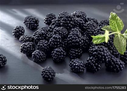 Close-up view on juicy and tasty blackberry fruits laying on grey table. Selective focus. Vitamins in fresh fruits concept.