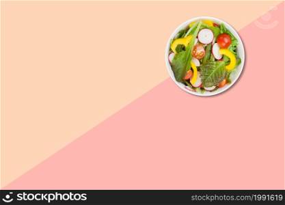 Close up view vegetable salad on brown plate isolated on pink background.