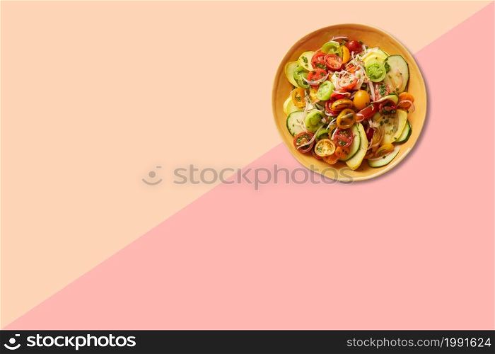 Close up view vegetable salad on brown plate isolated on pink background.