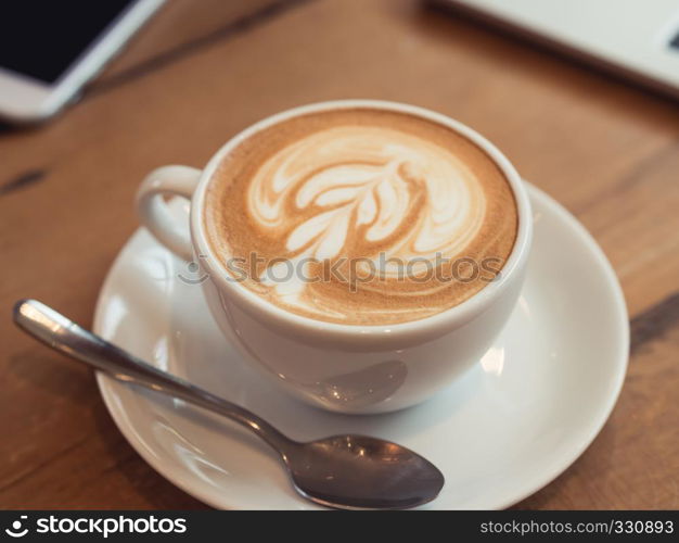 Close up white coffee cup with latte art on wood table at coffee shop
