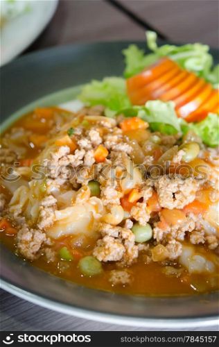 close up wide noodles with minced pork with tomato sauce served with fresh vegetable