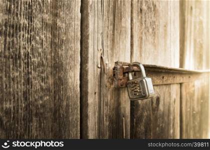 Close up with a metal lock on the door of an old wooden barn