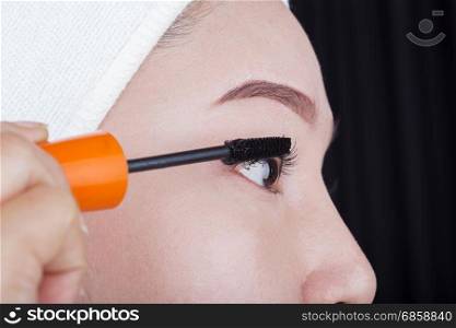 close-up woman applying mascara on her eyelashes