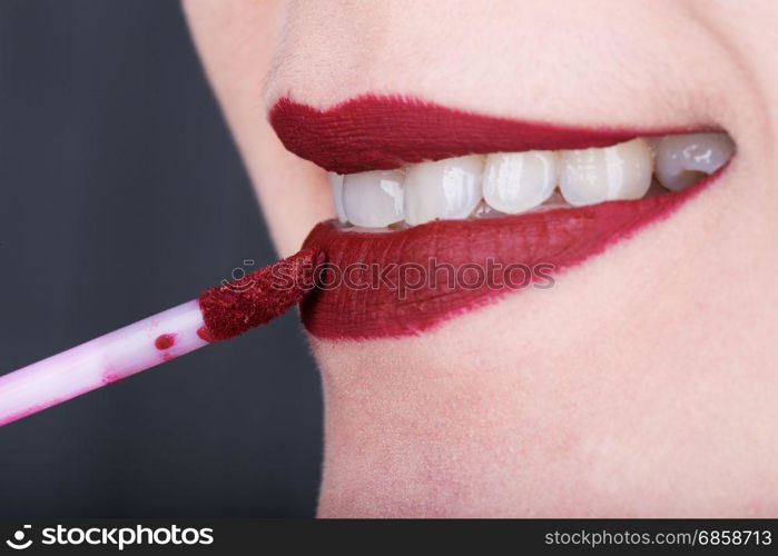 close-up woman applying red lipstick on her lips