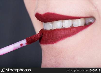 close-up woman applying red lipstick on her lips