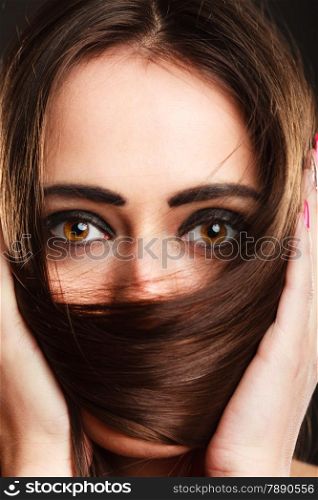 Close up woman covers the face by long brown hairs brown eyes with dark makeup
