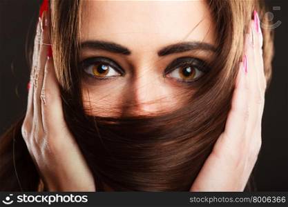 Close up woman covers the face by long brown hairs brown eyes with dark makeup