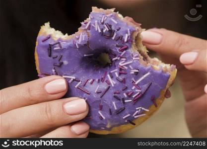 close up woman eating purple donut