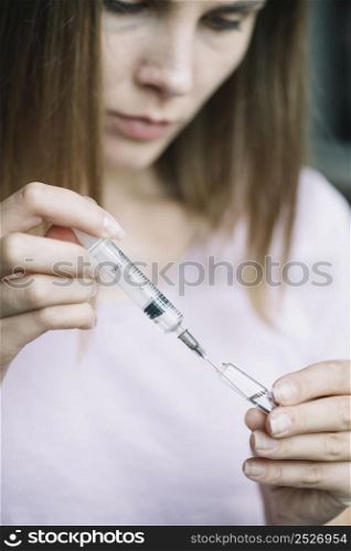 close up woman filling syringe with medicine