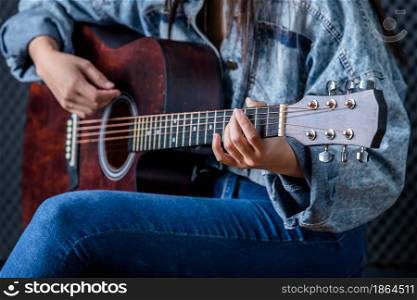 Close up woman fingers holding mediator with a Guitar recording a song in recording studio