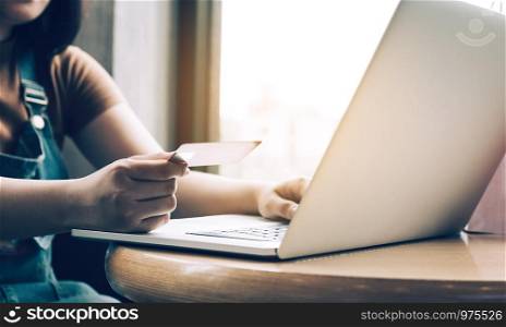 Close up woman hand holding credit card and typing keyboard laptop about shopping online concept.
