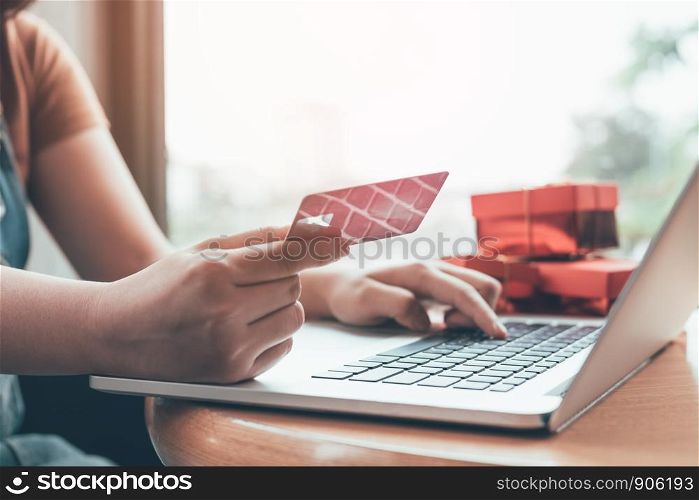 Close up woman hand holding credit card and typing laptop keyboard with shopping online concept.