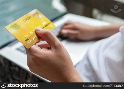 close up woman hand holding credit card and using laptop, online shopping concept