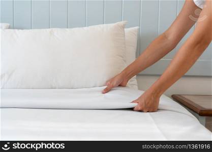 Close up woman hand set up white bed sheet in hotel room, copy space for text.