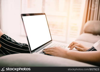 Close up woman hand typing trackpad and sitting on chaise longue and using laptop blank screen at home.