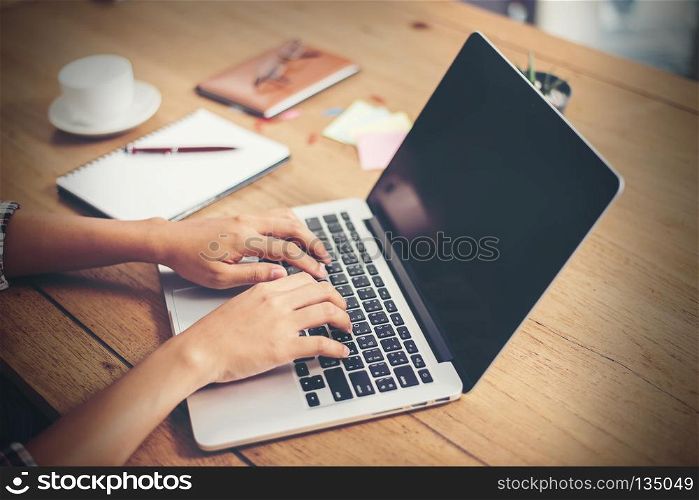 Close-up woman hands typing on laptop in office.