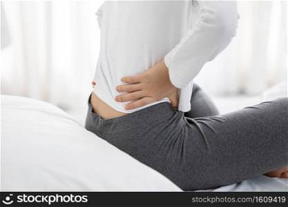 Close up woman have a back pain sitting on bed in bedroom feeling painful,Healthcare concept