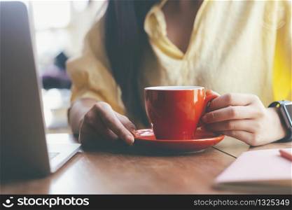 Close up woman holding a red cup of coffee to relax and rest from work.
