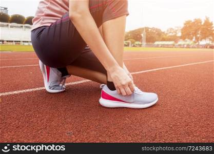 Close up woman is tie shoe in sport field