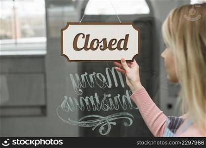 close up woman looking closed tag hanging glass storefront