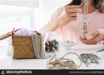 close up woman making chain bracelet with beads white desk