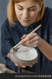 close up woman painting clay