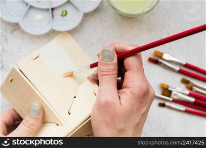 close up woman painting wooden house model with paintbrush