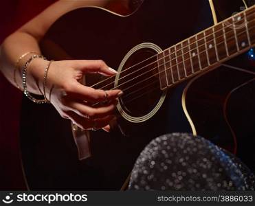 Close up, woman plays a guitar, smoky stage on background