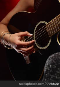 Close up, woman plays a guitar, smoky stage on background