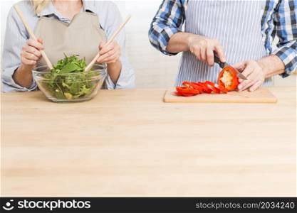 close up woman preparing salad her husband cutting bell pepper wooden table