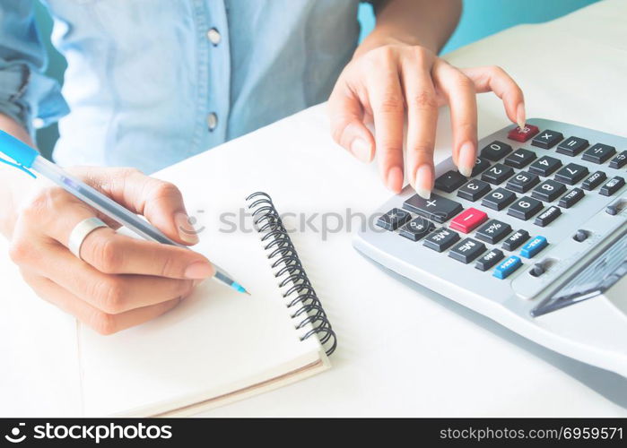 Close up woman&rsquo;s hands using calculator and writing on notebook,. Close up woman&rsquo;s hands using calculator and writing on notebook, Tax season, Business and finance