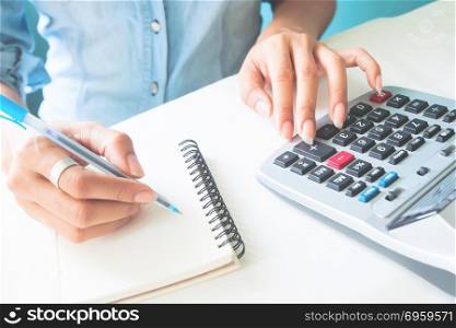 Close up woman&rsquo;s hands using calculator and writing on notebook,. Close up woman&rsquo;s hands using calculator and writing on notebook, Tax season, Business and finance