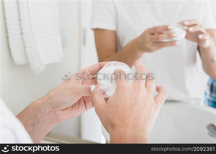 close up woman s hand applying moisturizer cream