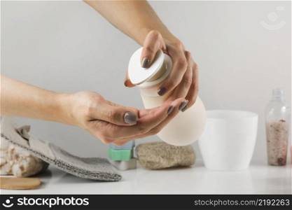 close up woman s hand pouring sanitizer soap from dispenser with spa product white desk against background