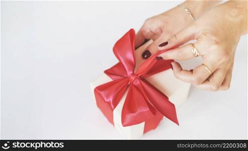 close up woman s hand unwrapping gift box white background