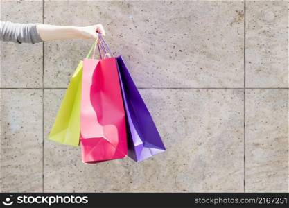 close up woman s hand with colorful shopping bags front wall