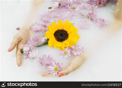close up woman s hand with yellow pink flowers floating water