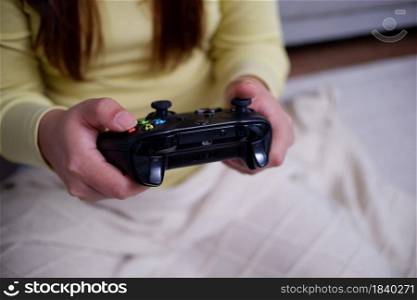 Close-up woman's hands holding joystick, playing video games in her apartment